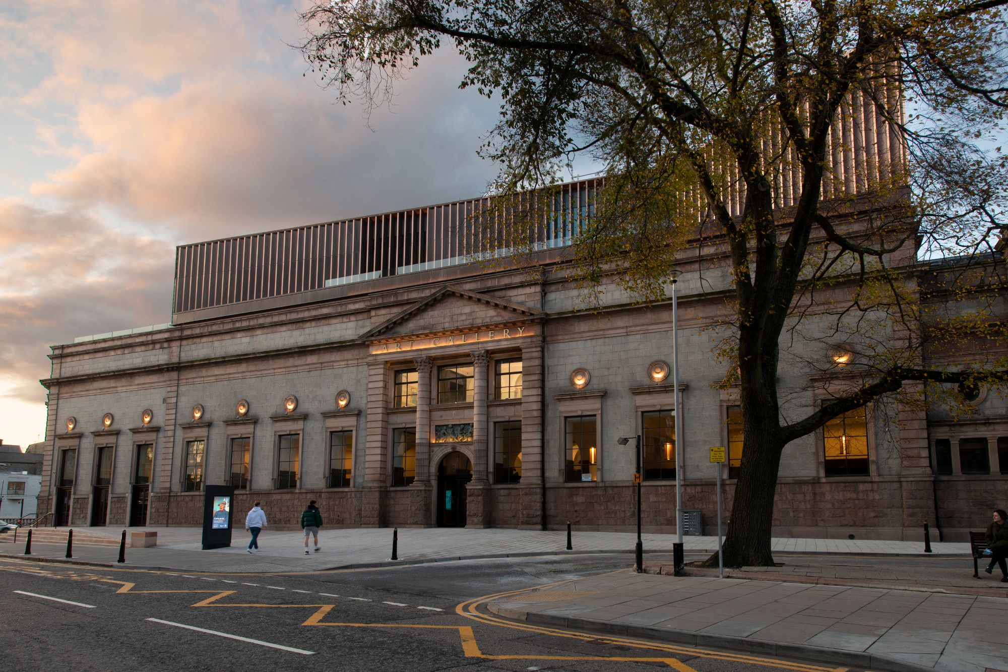 The entrance to Aberdeen Art Gallery. There is a large tree in front of the gallery, and the sun is setting.