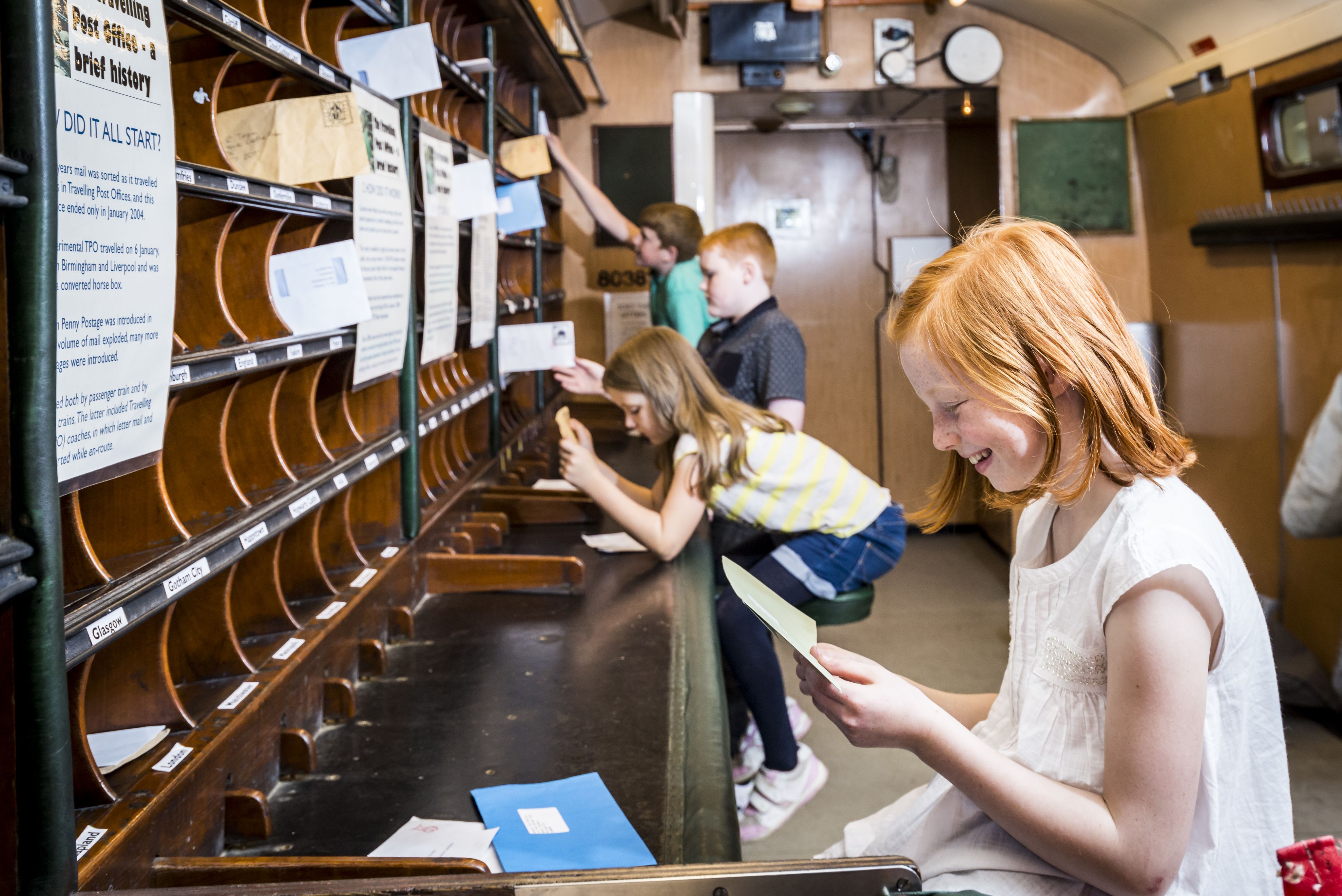 Children reading letters in a mail carriage at the Museum of Scottish Railways.
